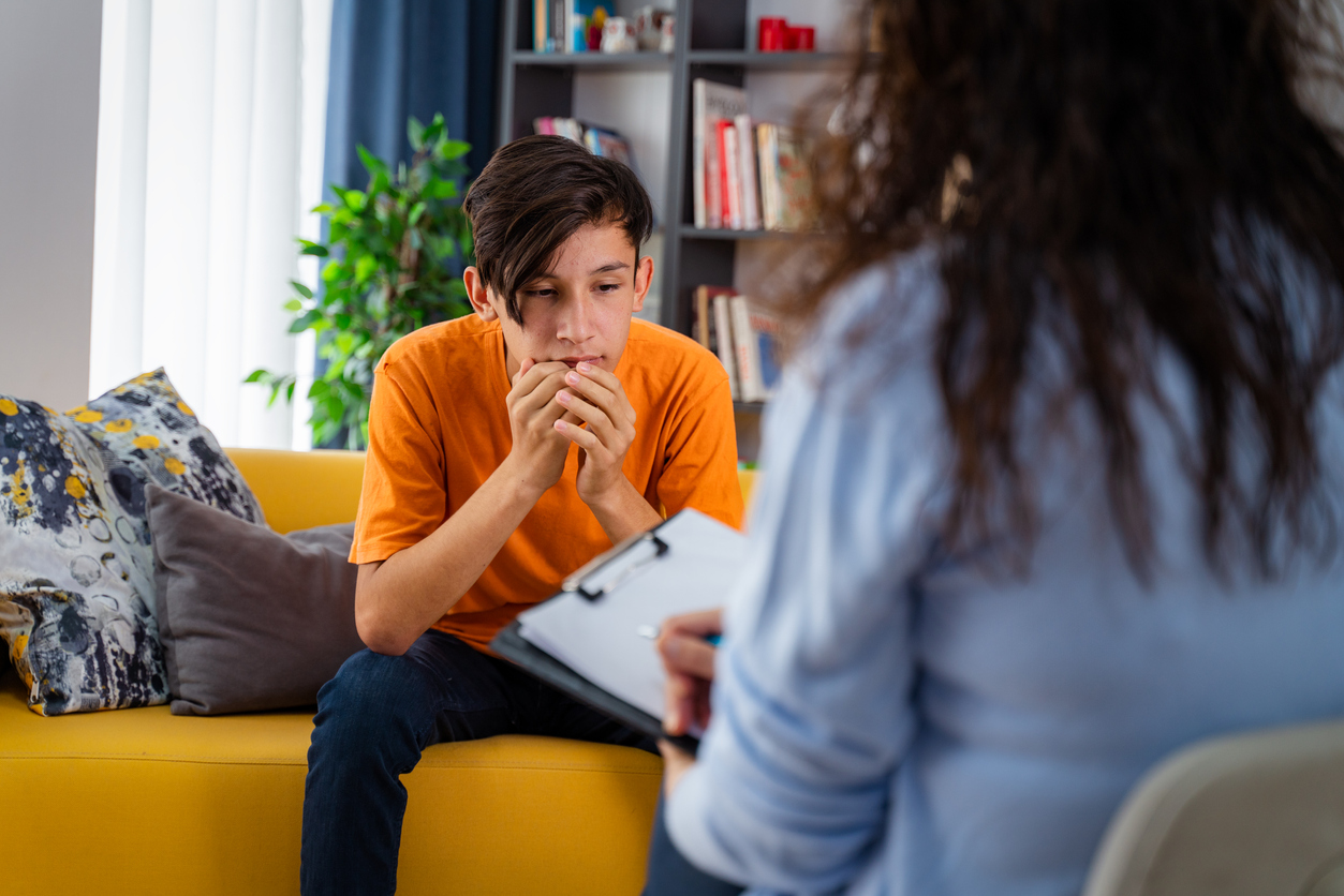 Female psychologist counseling teenage boy in office